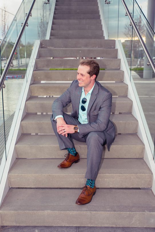 man wearing jord conway series walnut jet black unique wood watch joseph aboud gray suit steve madden shoes colorful socks sitting on outdoor staircase